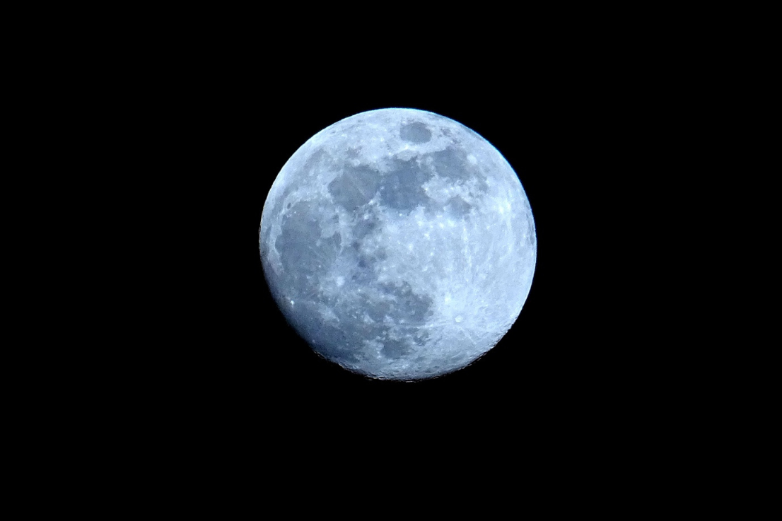 Luna llena vista de cerca, iluminada sobre un cielo nocturno completamente negro