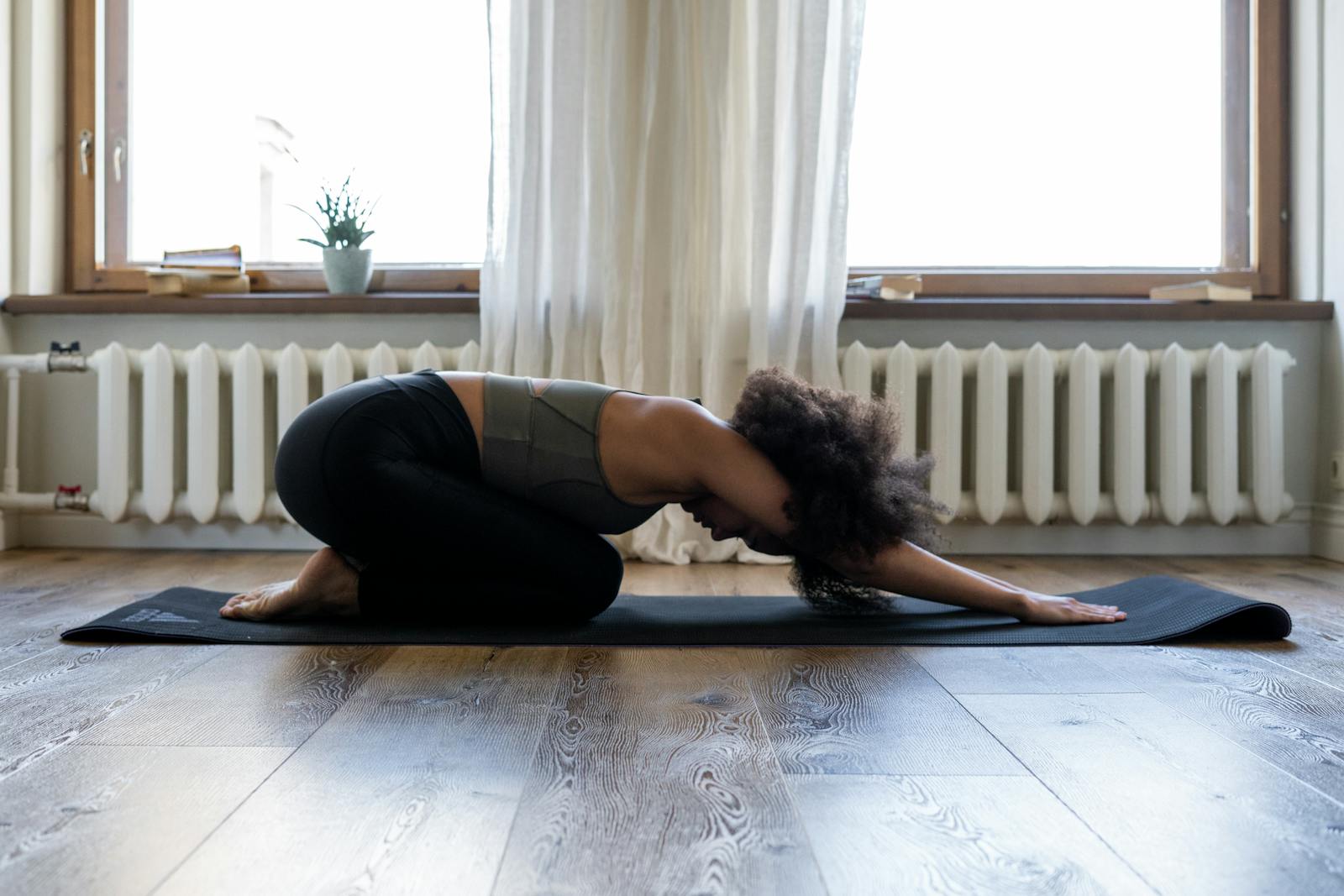 Mujer practicando yoga en el suelo en una habitación luminosa