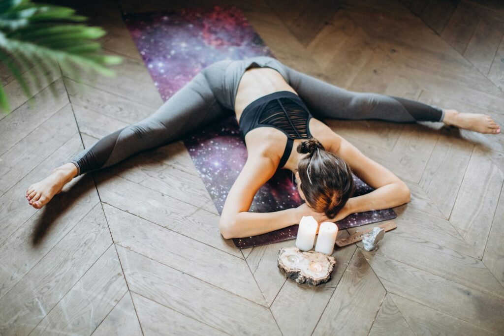 Mujer practicando yin yoga en el suelo rodeada de velas