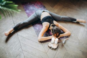 Mujer practicando yin yoga en el suelo rodeada de velas