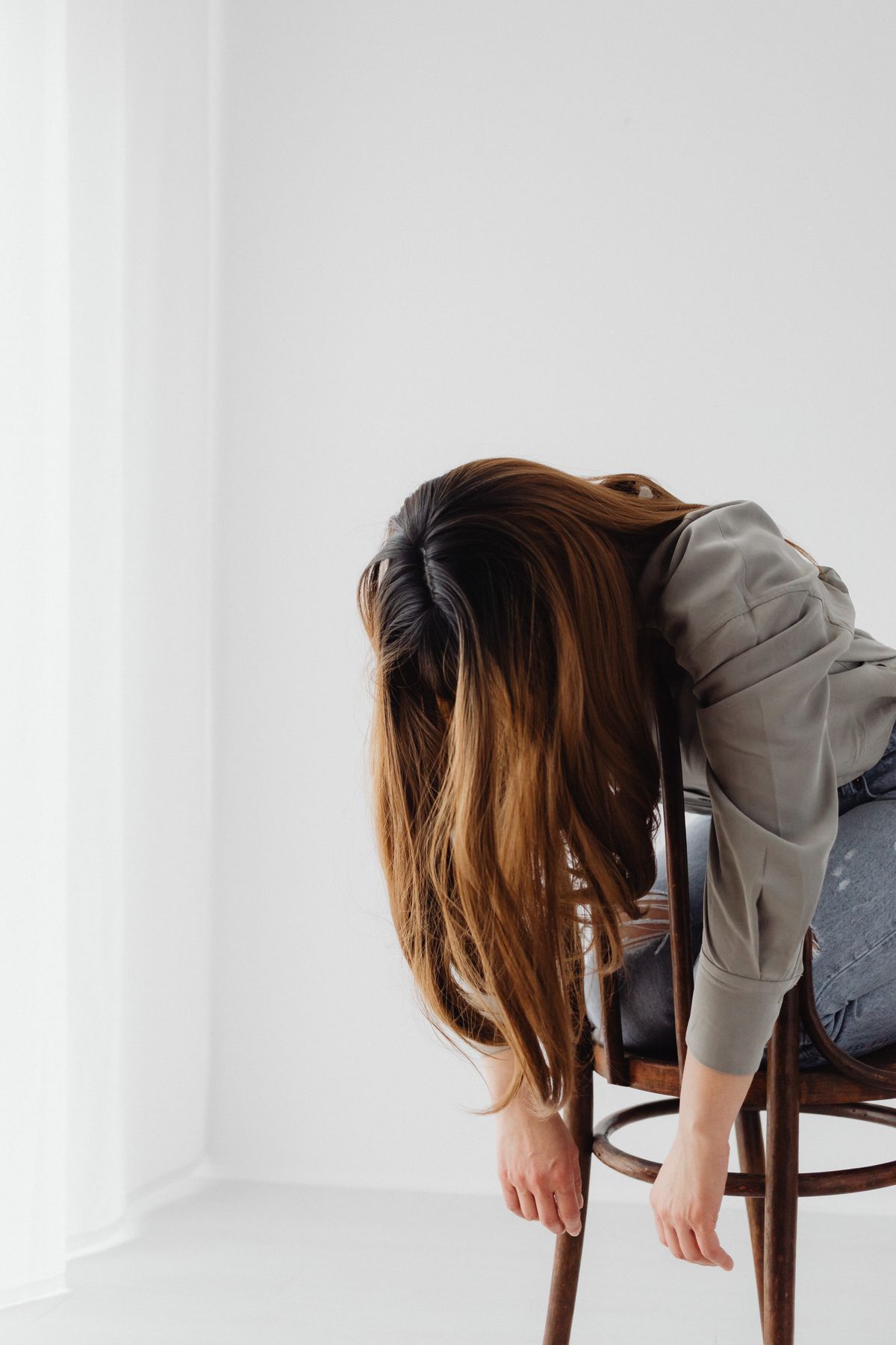 Yoga en la oficina: 10 ejercicios que puedes hacer en tu silla Mujer con ropa de trabajo doblada hacia delante sobre la silla, con los brazos colgando