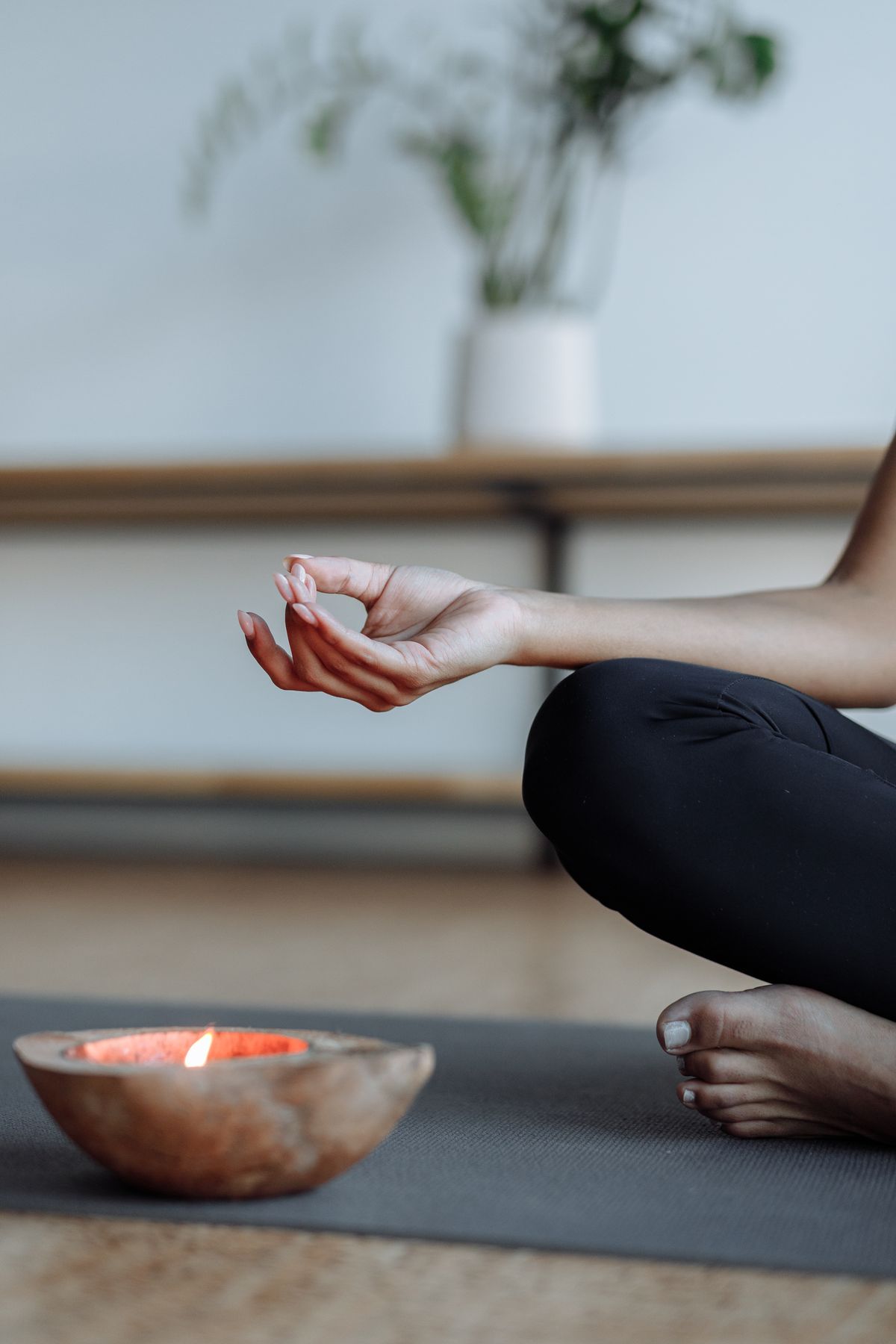 Yoga Mano en gyan mudra, con el pulgar y el índice unidos, junto a una vela encendida sobre la esterilla